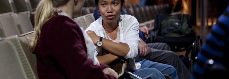Two woman sat in an empty theatre, speaking actively