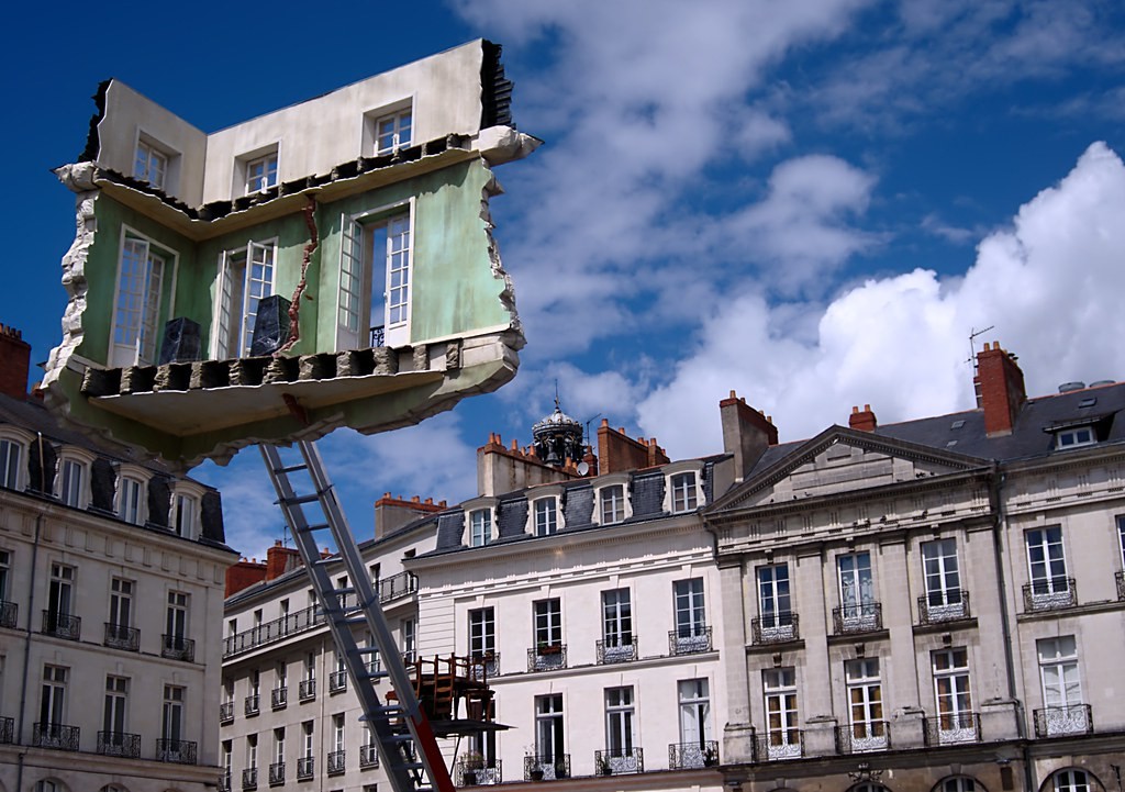 Picture of a torn apartment transported on a machine in the middle of a city square