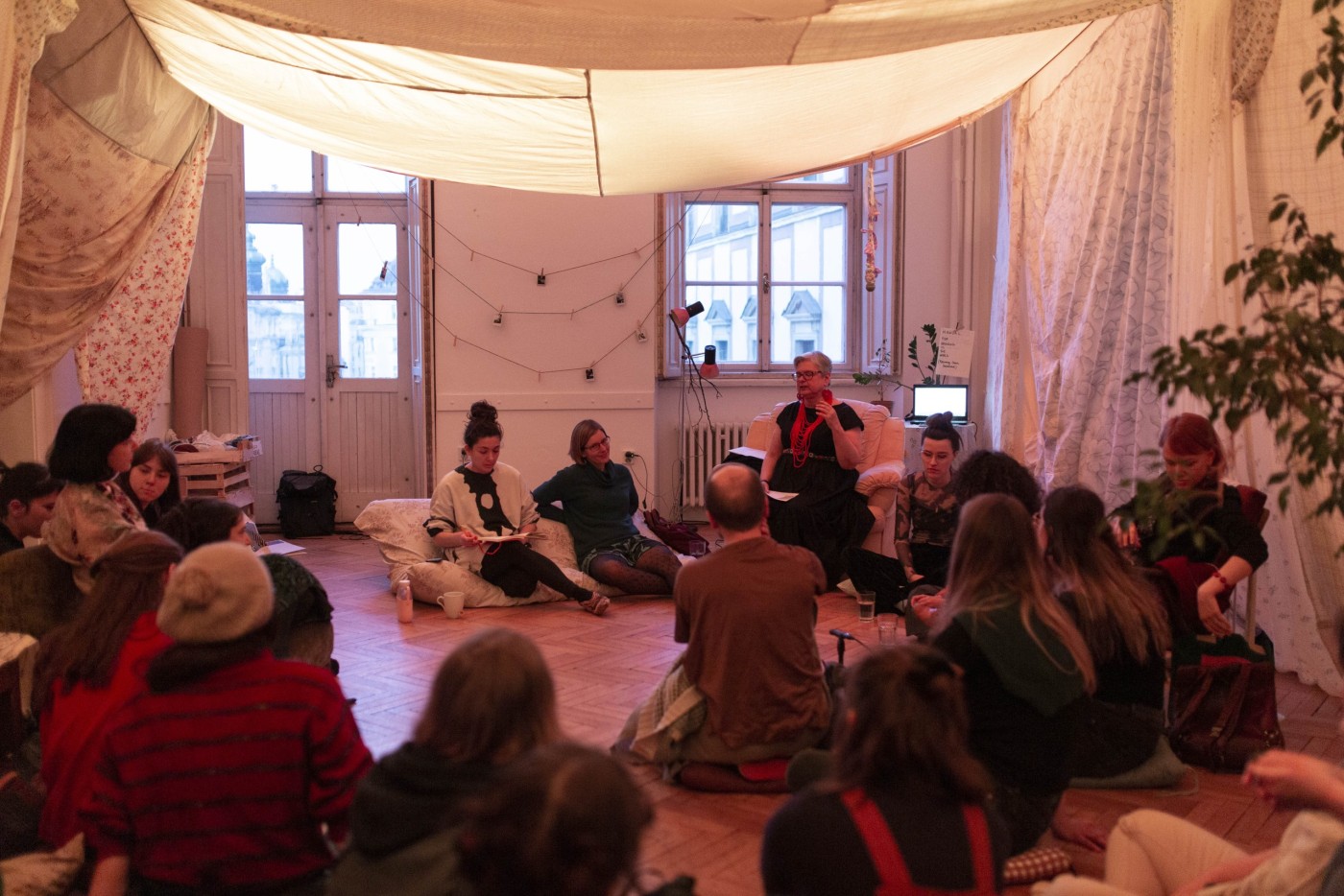 A cozy space where people are sat in a circle on the floor 