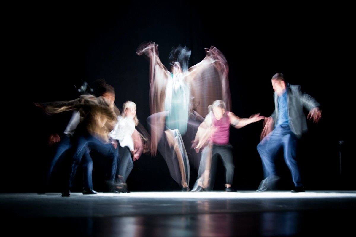 Picture of blurry people dancing on a dark stage
