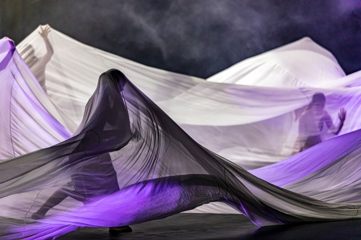 PIcture of people trapped under white and purple veils
