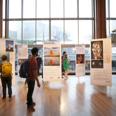 A small group of people looking at some posters of Unlimited Commissions, hung in the South Bank Centre
